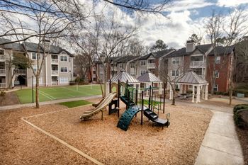 A playground with a green slide and a brown ground.
